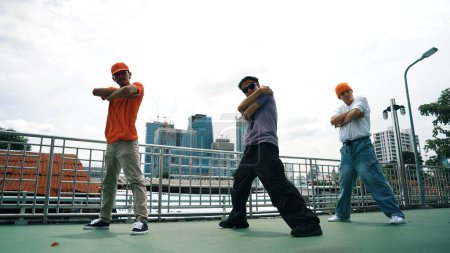 Group of skilled break dancer perform hip hop foot step together at rooftop with city or skyscraper view. Handsome hipster team moving to funky music at public place. Outdoor sport 2024. Sprightly.