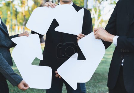 Photo for Business people holding pieces of reverse arrow icon into recycle symbol together in outdoor nature, promoting Earth cleaning day with zero waste pollution by embrace recycle reduce reuse idea. Gyre - Royalty Free Image