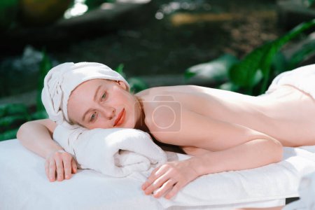 Téléchargez les photos : Portrait de jeunes femmes caucasiennes attrayantes avec une belle peau se trouve sur un lit de spa en attendant un massage du corps entouré d'un environnement naturel relaxant. Concept santé et beauté. Tranquillité. - en image libre de droit