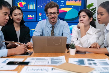 Photo for Diverse group of business analyst team analyzing financial data report. Finance data analysis chart and graph dashboard show on TV screen in meeting room for strategic marketing planning. Meticulous - Royalty Free Image