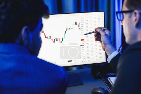 Photo for Two stock exchange traders cooperating digital currency or market online focusing on dynamic data monitor. Investor pointing to profit analyzing market stock at neon blue light workplace. Sellable. - Royalty Free Image