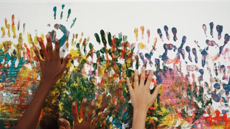Photo for Happy diverse student hand placed on colorful stained wall. Closeup of multicultural hand or children with mixed races paint their hand print at art room. Background. Creative activity. Edification. - Royalty Free Image