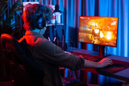 Photo for Host channel of young gaming streamer, team gamer playing battle game shooting with multiplayer at warship on pc screen with back side image, wearing headset with mic at digital neon room. Gusher. - Royalty Free Image