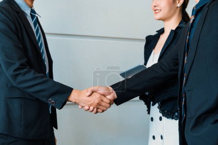 Photo for Business people agreement concept. Businessman do handshake with another businessman in the office meeting room. Young Asian secretary lady stands beside them. uds - Royalty Free Image