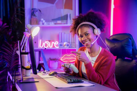 Photo for African American girl gaming streamer team winner playing online fighting with Esport wearing headphones in neon lighting room. Talking other players planing strategies to win competitors. Tastemaker. - Royalty Free Image