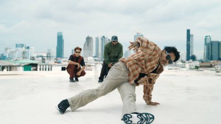 Photo for Professional hispanic break dancer practice B boy dance while multicultural friends at roof top. Young modern dancing group doing hip hop movement. Style,fashion,action. Outdoor sport 2024. Endeavor. - Royalty Free Image