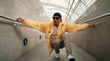 Photo for Skilled happy asian hipster walking while dancing in narrow corridor. Close up of break dancer practicing break dance performance. Professional man moving to music. Outdoor sport 2024. Sprightly. - Royalty Free Image