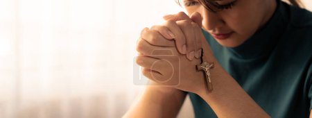 Photo for Young beautiful believer prays for happiness while holding crucifix.Concept of hope, religion, faith, christianity, spiritual, trust and god blessing.Bright white blurring background. Burgeoning. - Royalty Free Image