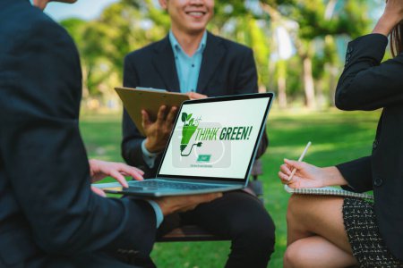 Téléchargez les photos : Groupe de gens d'affaires asiatiques qui planifient un plan de développement respectueux de l'environnement sur écran d'ordinateur portable et un projet de technologie durable pour un avenir plus vert, éco-bureau extérieur au parc naturel. Pneumatique - en image libre de droit