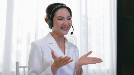 Téléchargez les photos : Femme d'affaires portant un casque de survie travaillant au bureau pour soutenir le client à distance ou un collègue. Le centre d'appels, le télémarketing, l'agent de soutien à la clientèle fournissent le service par vidéoconférence téléphonique - en image libre de droit