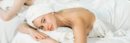 A beautiful young woman lies on a spa bed while looking at camera. Feeling of relaxed and at peace. Attractive caucasian woman with beautiful skin waiting for body massage. Closeup. Tranquility