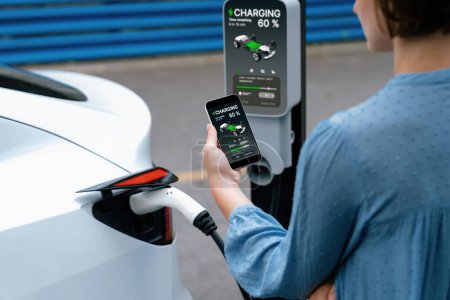 Branchez le chargeur EV main dans le véhicule électrique pour recharger la voiture EV, affichage de l'état de la batterie sur l'application smartphone EV. Énergie propre et durable future pour les transports. Perpétuel