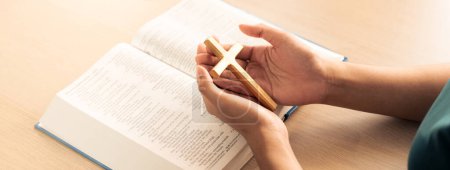 Photo for Female god believer holding wooden cross on opened holy bible book at light wooden church table. Top view. Concept of hope, religion, faith, christianity and god blessing. Warm background. Burgeoning. - Royalty Free Image