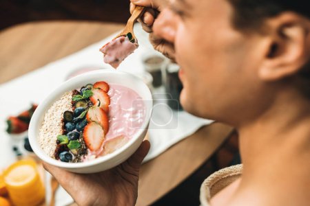 Foto de Foto enfocada en alimentos saludables ingredientes de yogur con fruta de bayas en la cara borrosa de la degustación de locutor inteligente, promoviendo con publicidad en línea para el beneficio de la vitamina y la fibra de cada comida. Pecuniario. - Imagen libre de derechos