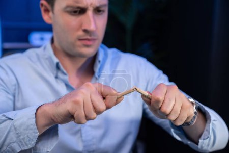 Photo for Stressful burnout of serious businessman destroying pencil for venting bad emotion in overwork load at night time. Concept of workload to solve issue problem at neon blue light of workplace. Sellable. - Royalty Free Image