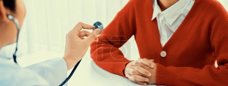 Photo for Patient attend doctors appointment at clinic or hospital office. Doctor examining and diagnosis symptoms while checking the patients pulse with stethoscope. Panorama Rigid - Royalty Free Image