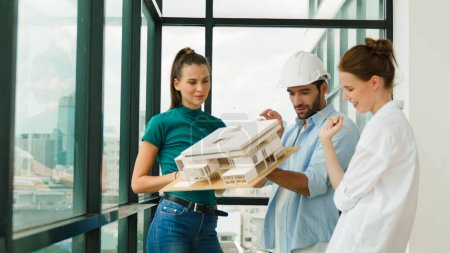 Photo for Skilled engineer holds house model and explain about house construction to skilled manager. Group of interior designer inspect architectural model. Working together, Civil engineering. Tracery - Royalty Free Image