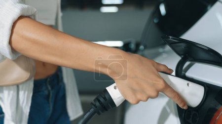 Photo for Young motion woman travel with EV electric car to shopping center parking lot charging station in downtown city sustainability lifestyle by green clean rechargeable energy of electric vehicle innards - Royalty Free Image