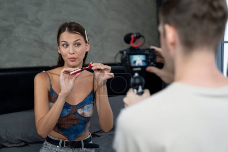 Photo for Man filming video on young woman making beauty and cosmetic tutorial video content for social media. Beauty blogger smiles to camera while showing how to beauty care to audience or follower. Unveiling - Royalty Free Image