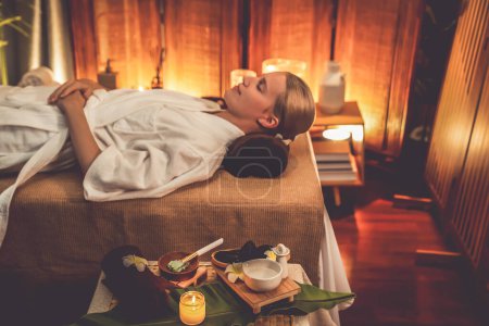 Photo for Aromatherapy massage ambiance or spa salon composition setup with focus decor candles and spa accessories on blurred woman enjoying blissful aroma spa massage in resort or hotel background. Quiescent - Royalty Free Image