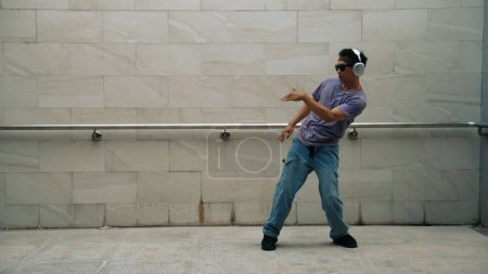 Photo for Motion shot of hipster listen music while move or dance to music at dancing room. Attractive street dancer practice b-boy footstep. Freestyle dance concept. Lifestyle. Outdoor sport 2024. Sprightly. - Royalty Free Image