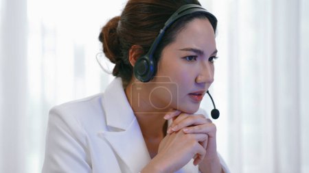 Photo for Businesswoman wearing headset working in office to support remote customer or colleague. Frustrated and tired call center customer support agent facing problem on providing vivancy service - Royalty Free Image