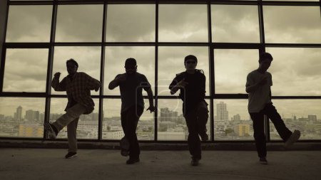 Photo for Silhouette shot of skilled choreographer group dancing together with sky scrapper, cityscape background. Young hipster team dancing performance. Sepia filter. Shadow. Outdoor sport 2024. Endeavor. - Royalty Free Image