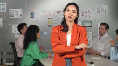 Téléchargez les photos : Femme d'affaires professionnelle asiatique debout avec confiance lors d'une réunion d'affaires créative. Belle leader confiant posant tandis que les gens d'affaires divers discussion sur l'utilisation Ux et Ui design - en image libre de droit