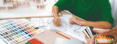 Photo for Professional architect drafts blueprint from project manager advice on table with house model, color palette and architectural equipment. Creative design concept. Focus on hand. Closeup. Variegated. - Royalty Free Image