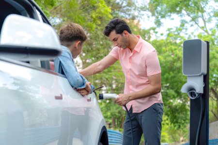 Photo for Family road trip vacation with electric vehicle, father and son recharge EV car with green and clean energy. Nature and travel with eco-friendly car for sustainable environment. Perpetual - Royalty Free Image