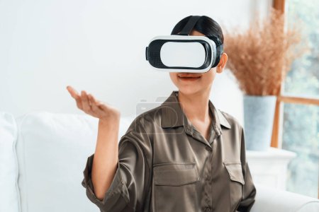 Téléchargez les photos : Jeune femme utilisant réalité virtuelle VR masque à la maison pour une expérience d'achat en ligne extrême. L'innovation VR en réalité virtuelle optimisée pour le divertissement numérique. - en image libre de droit