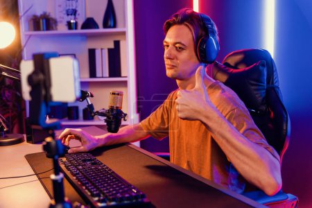 Photo for Host channel of gaming smart streamer playing online game, wearing headphone with viewers live steaming on media social online by smartphone talking with team player at neon lighting room. Pecuniary. - Royalty Free Image