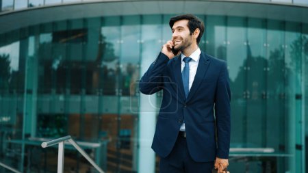 Photo for Skilled caucasian project manager calling phone while walking at city with blurred background. Skilled businessman using smart phone talking to project manager with blurred background. Exultant. - Royalty Free Image
