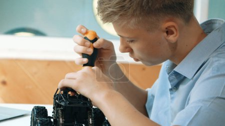Photo for Close up of young student tighten the nut by using screwdriver. Caucasian teenager repairing or fixing car model while inspect robotic machine construction at STEM technology class. Edification. - Royalty Free Image