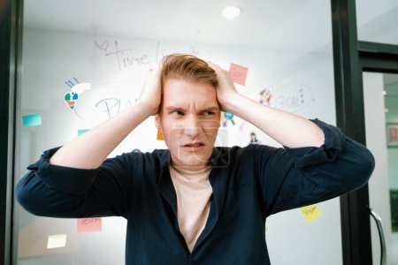 Photo for Portrait of young businessman frustrated, worried, disappointed, fail face expression while standing in front of glass board at creative business meeting. facing financial problems. Immaculate. - Royalty Free Image
