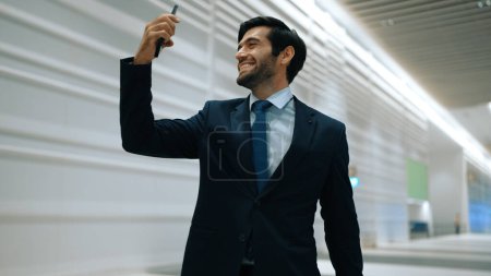Photo for Happy manager receive good news from mobile phone with white background. Smiling project manager getting promotion, getting new job, winning while taking selfie at train station. Exultant. - Royalty Free Image