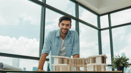 Photo for Portrait of engineer in casual outfit smiling at camera while inspect house model. Skilled architect looking at camera and standing near house model, project plan, architectural model. Tracery - Royalty Free Image