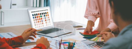 Photo for A portrait of creativity graphic designer team select appropriate color for the project by using laptop on table with equipment and designing tool scatter around at modern office. Closeup. Variegated. - Royalty Free Image