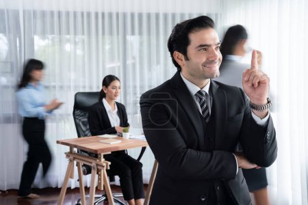 Téléchargez les photos : Portrait d'un homme d'affaires heureux regardant la caméra avec un fond flou de mouvement du mouvement des gens d'affaires dans une réunion d'affaires dynamique. Habillement - en image libre de droit