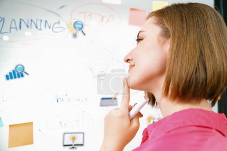 Portrait of young beautiful caucasian businesswoman thinking creative marketing strategy idea in front of whiteboard with mind map and colorful sticky notes. Arm chin. Closeup. Immaculate.