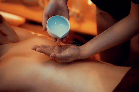Photo for Masseur hands pouring aroma oil on woman back. Masseuse prepare oil massage procedure for customer at spa salon in luxury resort. Aroma oil body massage therapy concept. Quiescent - Royalty Free Image