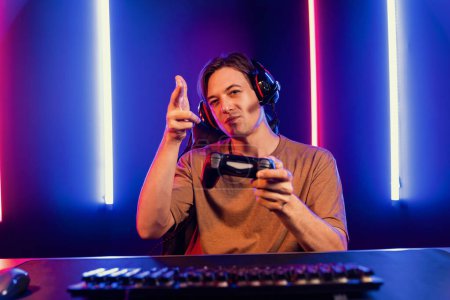 Photo for Enjoy smart gaming streamer with control joystick, playing game online of live streaming social media group with team skilled players on computer at modern technology cyber neon light room. Pecuniary. - Royalty Free Image