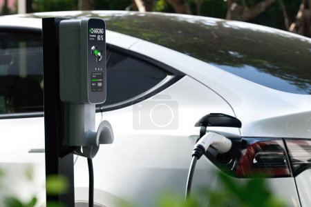 Téléchargez les photos : Chargement de voiture électrique EV dans le vert jardin extérieur durable de la ville en été. Style de vie urbain durable par vert propre énergie rechargeable des véhicules électriques BEV à l'intérieur - en image libre de droit