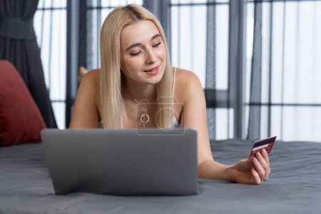 Photo for Young woman using laptop with credit card for internet banking, online shopping E commerce by online payment gateway at home office. Modern and convenience online purchasing with debit card. Blithe - Royalty Free Image