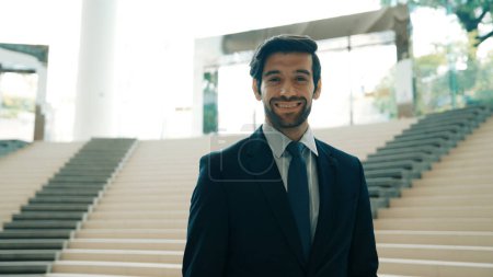 Téléchargez les photos : Portrait d'un homme d'affaires souriant regardant la caméra alors qu'il se tenait debout dans les escaliers. Gros plan de l'homme à succès souriant à la caméra tout en portant un costume d'affaires. Joyeux directeur exécutif regardez la caméra. Exultant. - en image libre de droit