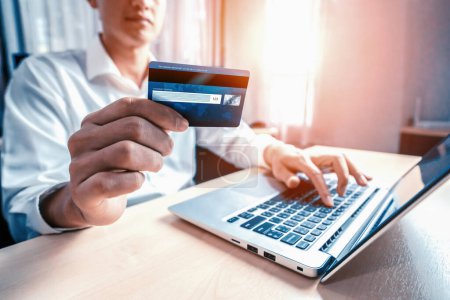 Foto de Hombre joven utilizar la tarjeta de crédito para el pago de compras en línea en la aplicación de ordenador portátil o sitio web. Concepto de comercio electrónico y compras en línea. BARROS - Imagen libre de derechos
