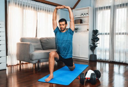 Photo for Athletic and sporty man doing warmup and stretching before home body workout exercise session for fit physique and healthy sport lifestyle at home. Gaiety home exercise workout training concept. - Royalty Free Image
