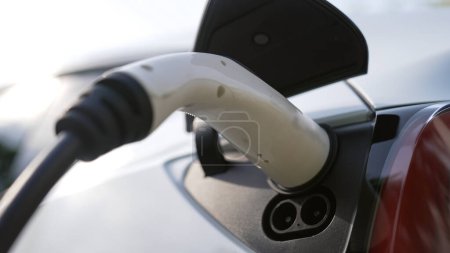Nahaufnahme EV-Ladesteckerhalter verbinden sich mit Elektroautos und laden EV-Autobatterie mit alternativer und nachhaltiger Energie ohne CO2-Emissionen für eine saubere Umwelt auf. Synchronos