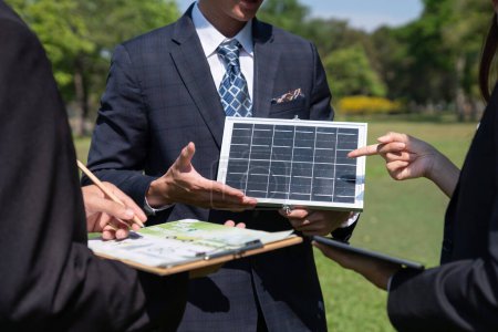 Téléchargez les photos : Réunion d'affaires en plein air sur l'énergie solaire, groupe de gens d'affaires travaillant et brainstorming sur l'utilisation des technologies d'énergie alternative comme engagement de l'entreprise à l'effort de RSE. Pneumatique - en image libre de droit