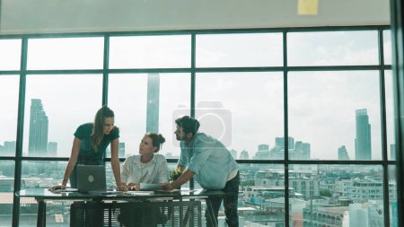 Photo for Group of happy skilled businesspeople discuss, brainstorming, sharing idea, plan, strategy about financial statistic on meeting table with laptop and statistic document. Cityscape view. Tracery - Royalty Free Image